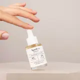 En hand håller en flaska Apoliva Niacinamid Serum, en viktig del av din niacinamide hudvård för en jämnare hy.
