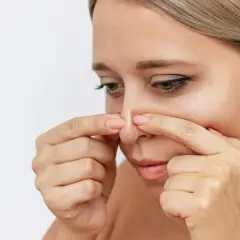 En kvinna undersöker sin näsa, kanske funderar på hur man får bort pormaskar.