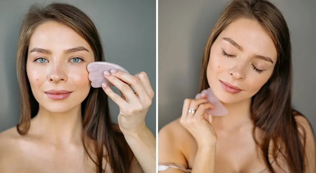 Kvinna använder en rosa gua sha för ansiktsmassage.