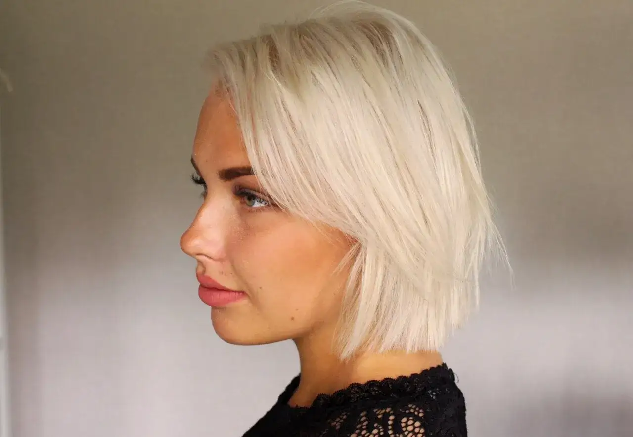Profilbild p&aring; en kvinna med blont h&aring;r och ljus hy. Hennes &ouml;gon &auml;r gr&ouml;na och hon har rosa l&auml;ppar. H&aring;ret &auml;r kortklippt och stylat med en sidbena. Hon b&auml;r en svart spetskl&auml;nning. Det finns fyra anledningar till att hennes h&aring;r ser ut som frusen sand.