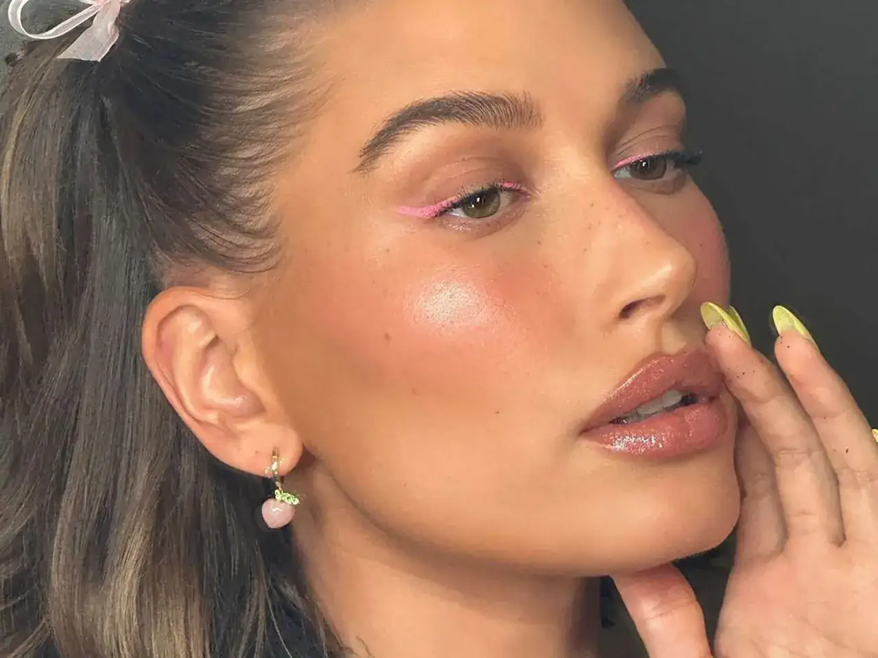 En kvinna med rosa eyeliner och glansiga l&auml;ppar. Hennes ansikte &auml;r skulpterat med rouge och highlighter.